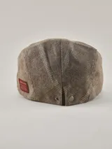 Boina de estilo clásico en color visón con patrón de espiga sutil. Presenta una etiqueta rectangular roja con el logo de la marca en el lateral.