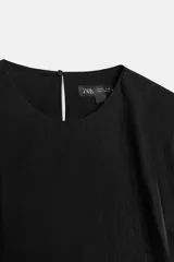 Top negro de manga sisa de Zara Woman Collection, confeccionado en mezcla de algodón, con cuello redondo y bajo acabado en peplum fruncido.
