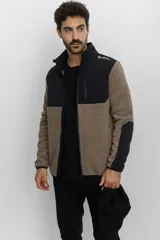 Campera de polar con cierre frontal completo, diseño bicolor en tonos negro y marrón. Cuenta con cuello alto, bolsillo con cierre en el pecho y paneles reforzados en los hombros y mangas.