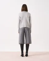 Sweater gris claro de tejido de punto con cuello alto acanalado. Presenta un diseño vertical en el centro delantero y trasero, punto diferencial en las mangas, ruedo con tajo lateral y puños acanalados.