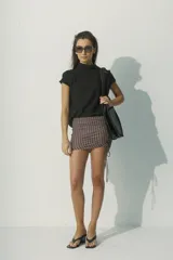 Blusa de lino color negro, con cuello alto y mangas cortas con detalle de costura decorativa en los hombros. Presenta un diseño minimalista de silueta recta y tejido liviano.