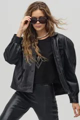 Chaqueta negra de cuero de oveja con apliques tribales en gamuza de cabra al tono, forro capitoneado de poliéster, cuello camisero redondeado, bolsillos frontales, bolsillo interno y botones metálicos a presión forrados.