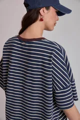 Remera oversize a rayas horizontales en tonos bordó y blanco, con cuello redondo verde oscuro y un pequeño parche bordado en forma de corazón en el pecho.