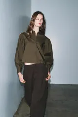 Camisa de popelín color blanco con cuello solapa, cierre frontal con botones ocultos y mangas largas abullonadas con puños estructurados.