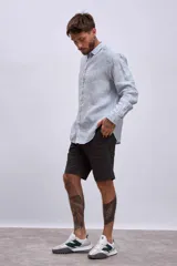 Camisa de manga larga para hombre, con cuello clásico y botones frontales. Presenta un estampado de rayas verticales finas en tonos azul claro y blanco.