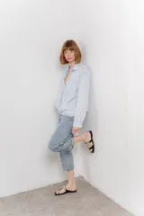 Camisa color crema de algodón con cuello camisero, botones y detalles de encaje en el escote.