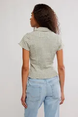 Camisa de mezcla de algodón y lino, de cuerpo entallado, con diseño a cuadros en tonos verde y beige. Presenta escote en V con cuello de solapa, mangas cortas y cierre frontal con botones.