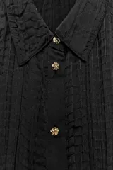 Camisa de manga larga con cuello solapa, confeccionada en tejido satinado con textura efecto arrugado y cierre frontal con botones.