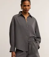 Camisa gris de tejido plano con corte sastre, cuello clásico, abotonada en el frente y puños largos.