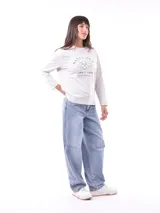 Remera de manga larga color crema con cuello redondo y un estampado central de un ramo de flores rosadas y naranjas en un jarrón azul oscuro.