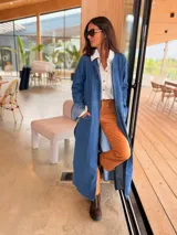 Tapado largo de jean azul, con diseño abierto sin botones, mangas largas y tajos laterales profundos. Confeccionado en denim suave y flexible.