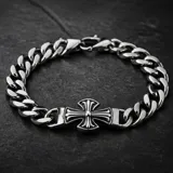 Pulsera de eslabones gruesos de acero con dije central en forma de cruz con detalles grabados.