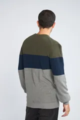 Sweater de tejido de punto con diseño color block en tonos verde, azul y gris. Presenta cuello redondo, mangas largas y corte regular.