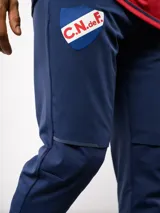 Pantalón de entrenamiento Umbro del Club Nacional de Football, color azul marino. Presenta un diseño técnico con paneles reforzados en la zona de las rodillas, escudo del club en el muslo derecho y logo de la marca en el izquierdo.