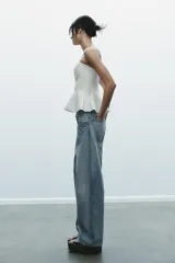 Top color amarillo claro, sin mangas y con escote recto. El bajo tiene un acabado peplum.