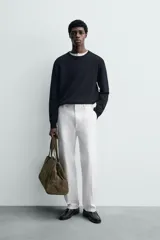Pantalón chino de corte oversized confeccionado en tejido de algodón con estructura twill. Presenta bolsillos frontales, bolsillos traseros de vivo y cierre frontal con cremallera y gancho metálico oculto.