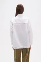 Camisa de algodón color blanco, de corte holgado y manga larga. Presenta detalles de encaje tipo puntilla en el frente, espalda y mangas, con cierre frontal de botones y cuello camisero clásico.