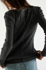 Remera manga larga tipo henley de algodón con cierre frontal de botones y costuras visibles. Presenta un ajuste al cuerpo y textura acanalada.