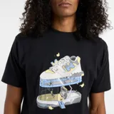 Remera negra de algodón con cuello redondo y mangas cortas. Estampado frontal con diseño de zapatillas New Balance en un centro de fitness.