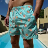 Short de baño color turquesa con estampado de rodajas de naranja, cintura elástica con cordón ajustable y parche circular con logo en el ruedo.