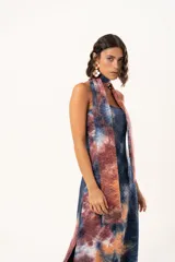 Vestido largo de corte recto y escote strapless, con estampado estilo batik en tonos azul, naranja y bordó. Incluye una bufanda larga integrada al diseño que cae desde el cuello.