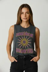 Musculosa de algodón color gris oscuro con cuello redondo y diseño sin mangas. Presenta un estampado frontal estilo vintage con la leyenda 'sunset dream usa tour 1975' y un gráfico de sol en tonos amarillos y violetas.