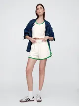 Short de piqué color crema con ribetes en color verde, cintura elástica con cordón de ajuste y diseño deportivo.