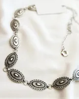 Cinturón plateado con eslabones ovalados con diseño floral.