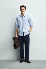 Camisa regular fit de manga larga con diseño a rayas verticales celestes y blancas. Cuenta con cuello abotonado, bolsillo de parche en el pecho y cierre frontal con botones.