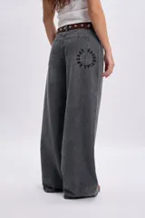 Pantalón jean ancho color gris claro, de corte holgado y tiro medio con estampa circular en el bolsillo trasero.