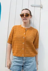 Saco tejido calado color ocre, con mangas al codo y botones de coco. Tiene grifa de cuero en la espalda.