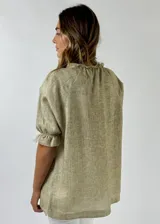 Blusa de lino color azul claro con textura jaspeada, escote en V y mangas cortas con elástico fruncido en los puños.