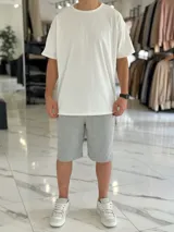 Remera blanca oversize de manga corta, con diseño texturado de líneas finas verticales y cuello redondo.