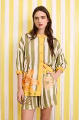 Short con estampado a rayas verticales en tonos verde y blanco, con cintura elastizada y detalle de estampado floral y texto.