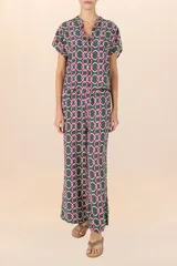 Camisa verde con estampado de cadenas entrelazadas en tonos verde oscuro, blanco y fucsia, de mangas cortas y cuello camisero.