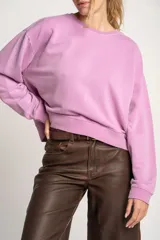 Buzo lila oversize confeccionado en 100% algodón, con cuello redondo, mangas largas y puños y dobladillo acanalados. Presenta un pequeño detalle bordado en el bajo.