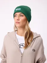 Gorro tipo beanie de tejido de punto acanalado en color marrón, con parche rectangular frontal con el logo de la marca Rusty.