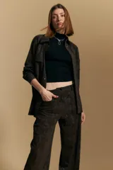 Pantalón de corte ancho y silueta relajada, confeccionado en tejido de efecto gamuzado color marrón oscuro. Presenta un diseño de tiro alto con cierre frontal y bolsillos laterales.