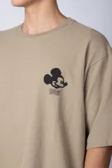 Remera negra de corte oversize confeccionada en algodón pesado, con estampa pequeña de Mickey Mouse en el pecho y diseño gráfico en la espalda.