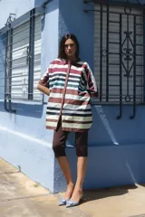 Camisa blanca de corte oversize y largo midi, confeccionada en algodón. Presenta cuello mao, cierre frontal oculto por tapeta y mangas cortas con dobladillo. Incluye un pequeño bordado de una flor en el pecho.