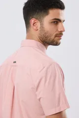 Camisa lisa de algodón azul marino, de manga corta, con cuello camisero, cierre frontal de botones y un bolsillo aplicado en el pecho.