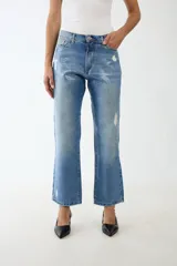 Jean de algodón 100% con lavado azul medio, tiro alto y corte recto/acampanado. Presenta un estampado texturizado tipo cocodrilo en tono más claro y detalles de desgaste/roturas.