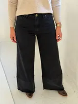 Pantalón de jean negro de corte wide leg con diseño de costura horizontal en el ruedo y terminación deshilachada. Cuenta con cierre frontal y bolsillos laterales.