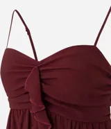 Blusa tipo bata color bordó, confeccionada en crepé, con breteles finos ajustables, busto fruncido y detalle de volado vertical en el frente. Posee espalda con lastex para un mejor ajuste.