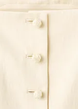 Top de lyocell color beige, diseño recto con escote cuadrado, sin mangas, tirantes finos y cierre frontal con botones.