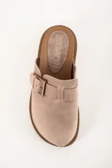 Zueco color beige de cuero con hebilla metálica ajustable y suela marrón con textura.