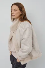 Chaqueta de piel sintética en color burdeos, con cuello alto y cierre frontal oculto. Presenta un diseño de corte recto y mangas largas con puños ligeramente ajustados.