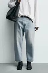 Jeans de hombre color azul claro con efecto lavado, de corte relajado desde la cadera que se estrecha ligeramente en el bajo. Tienen tiro medio, cinco bolsillos y cierre frontal con cremallera y botón.