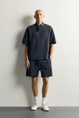 Bermuda estilo jogger de ajuste relajado, confeccionada en tejido interlock de algodón. Cuenta con cintura elástica ajustable con cordón, bolsillos frontales de vivo y diseño liso.