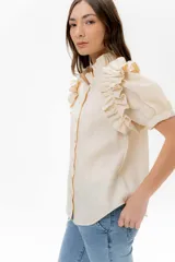 Camisa celeste de lino con cuello mao y mangas cortas abullonadas con volados. Cierre frontal con botones.